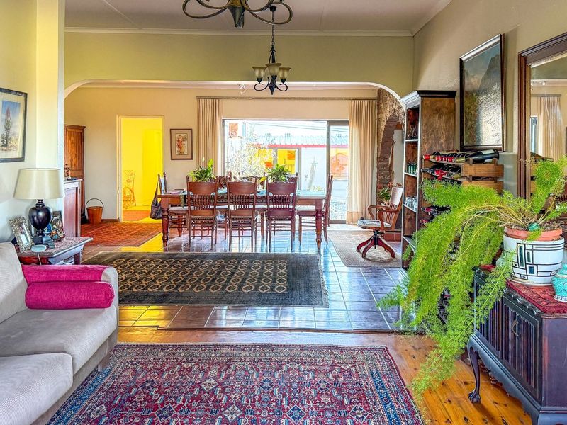 Spacious open-plan living and dining area featuring a blend of timber and tiled flooring, an arched transition, and direct access to the outdoor space.