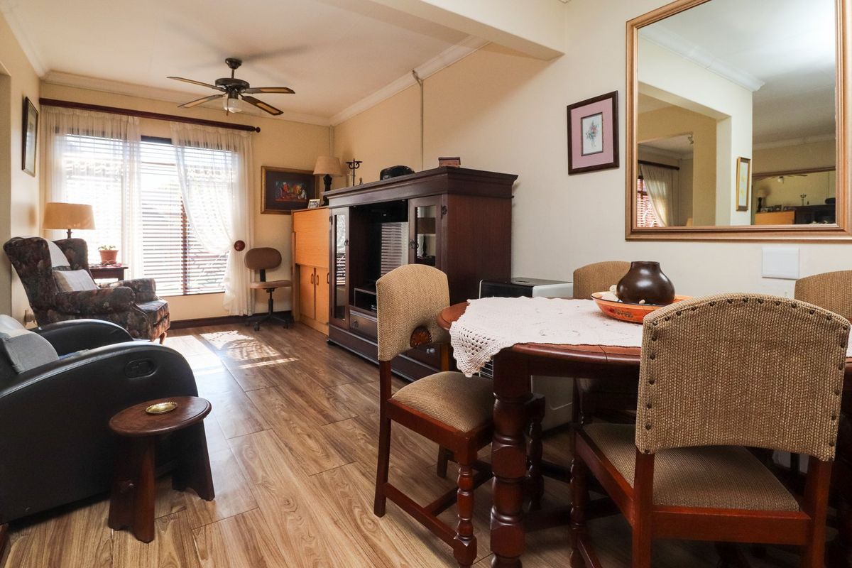 A living and dining area featuring laminate flooring, a ceiling fan, and crown molding, providing a functional space with natural light.