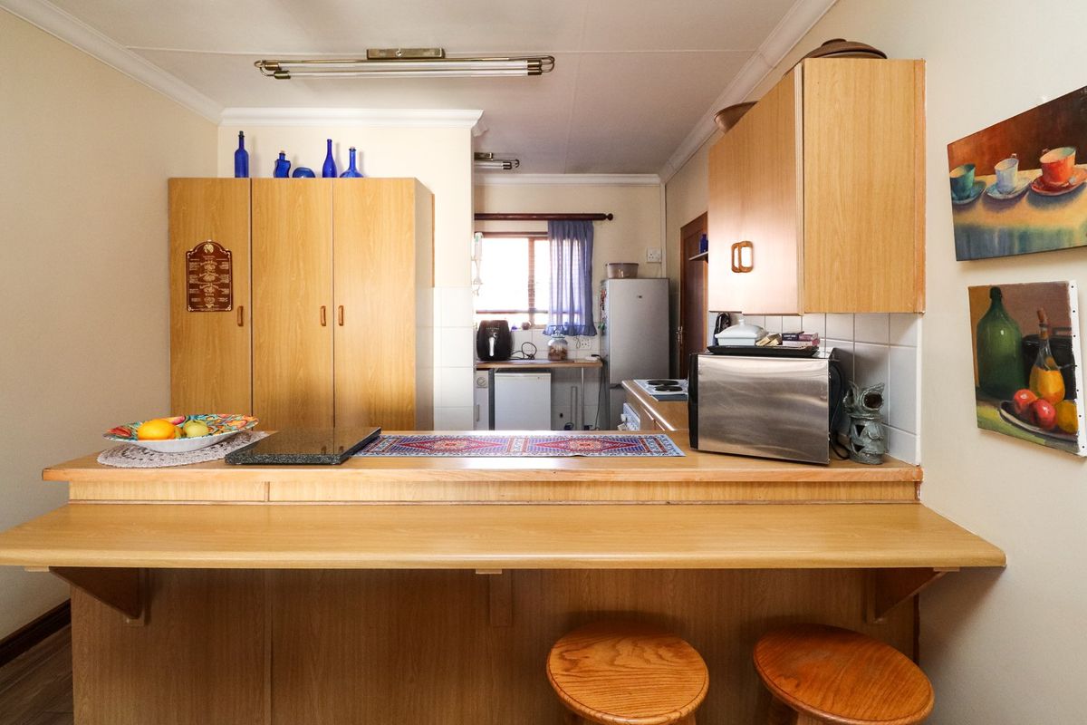 A functional kitchen featuring wooden cabinetry, a breakfast bar, and a tiled backsplash, offering a practical layout with potential for modern updates.