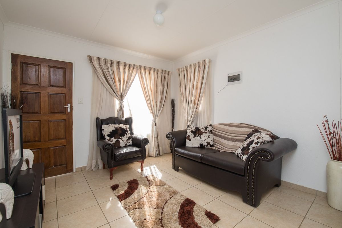 A living room featuring tiled flooring, a timber entrance door, and a wall-mounted electrical distribution board.