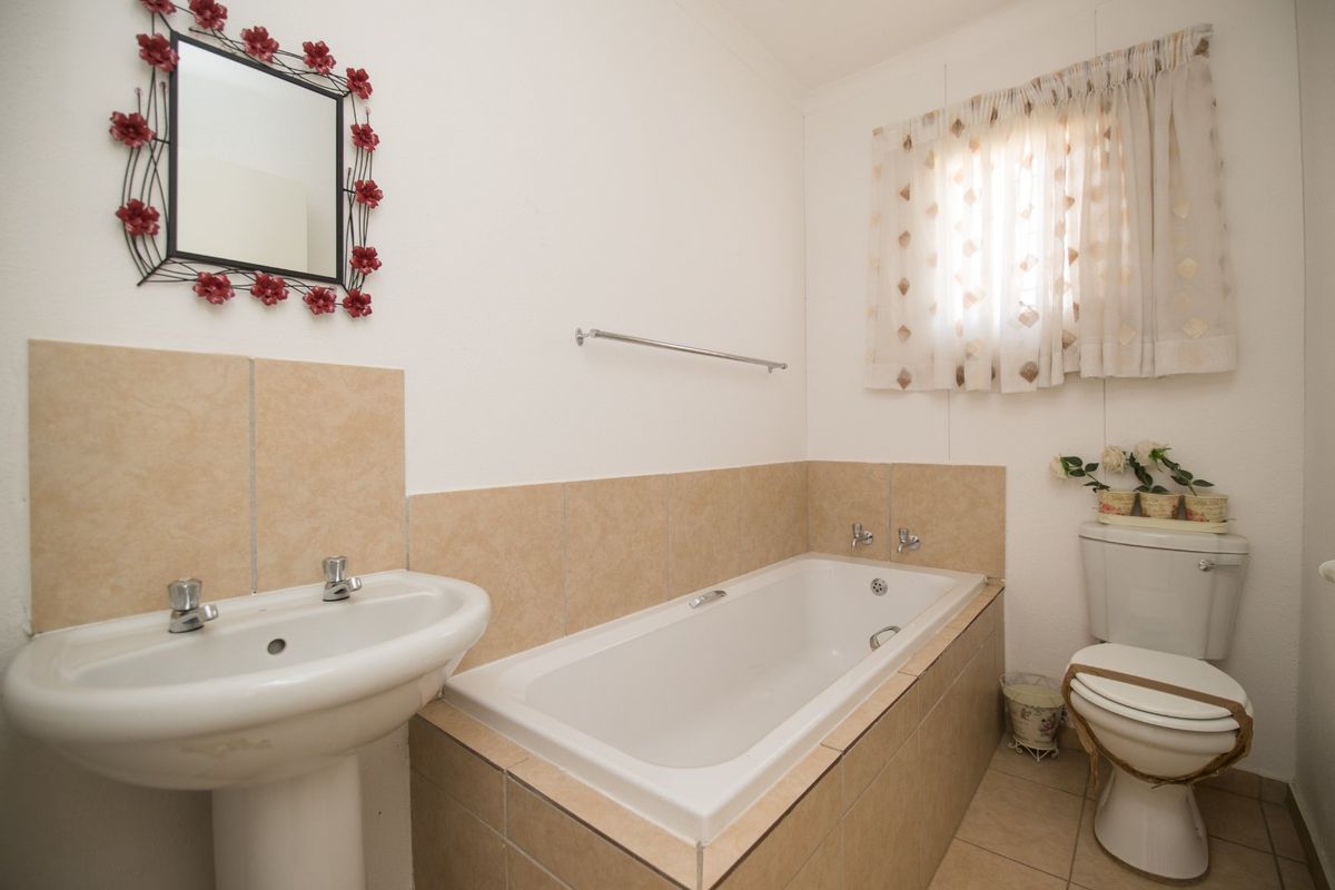 A functional bathroom featuring a pedestal basin, a built-in bathtub with tiled surround, and a standard toilet with neutral ceramic finishes.