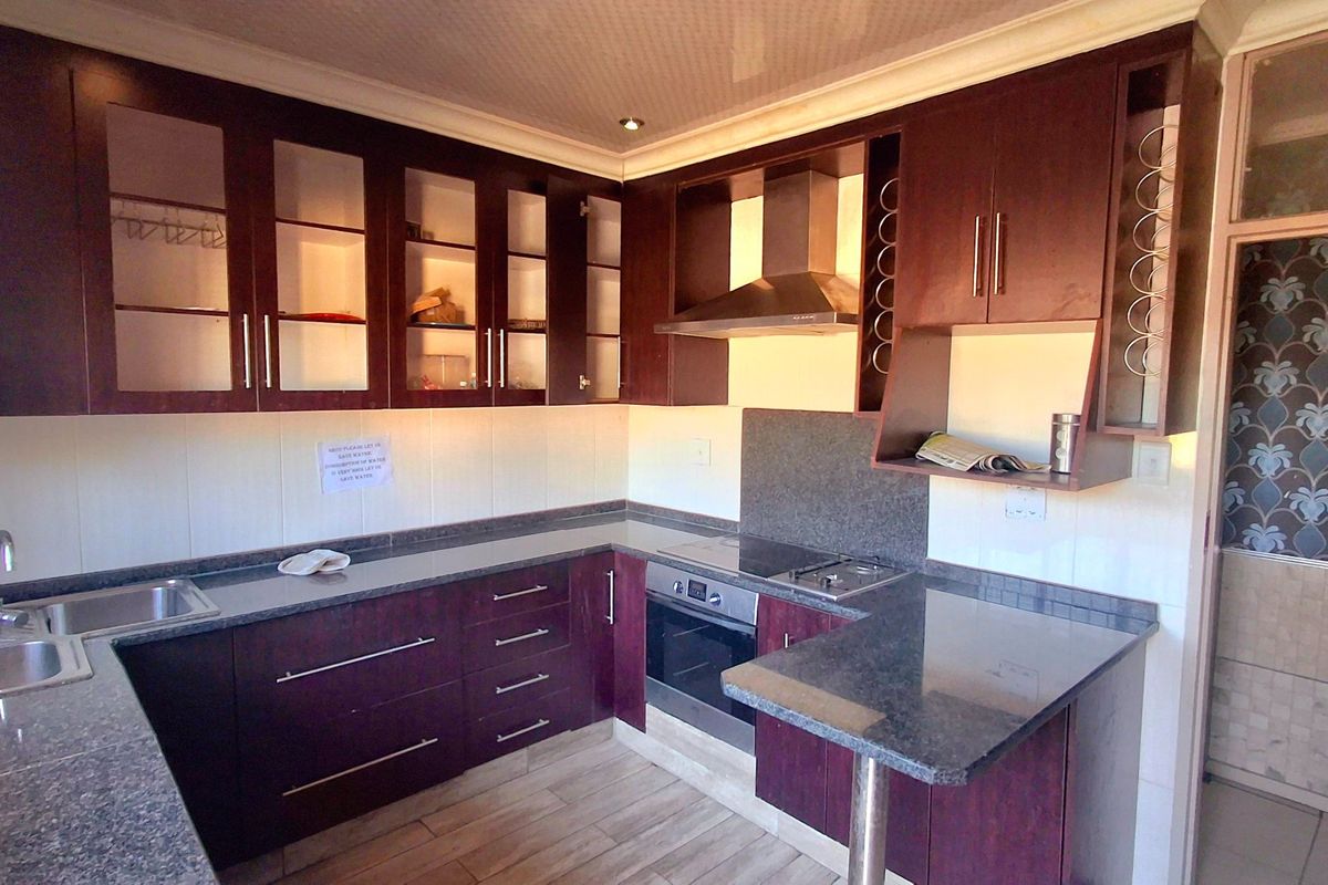 A well-maintained kitchen featuring dark wood cabinetry, granite countertops, a built-in oven, and a breakfast bar, offering a functional and clean workspace.