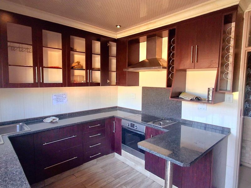 A well-maintained kitchen featuring dark wood cabinetry, granite countertops, a built-in oven, and a breakfast bar, offering a functional and clean workspace.