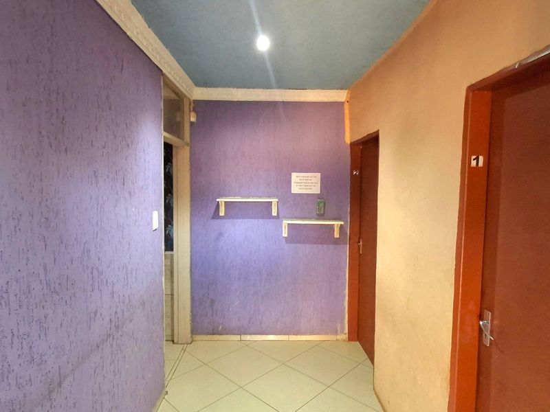 A functional hallway featuring tiled flooring, built-in wall shelving, and multiple internal access doors.