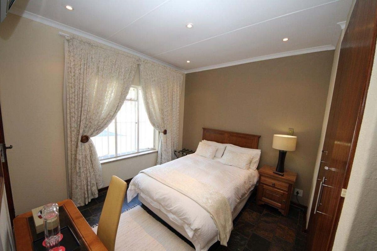 A cozy bedroom featuring tiled flooring, recessed downlighting, and built-in wooden cupboards, offering a functional and comfortable living space.