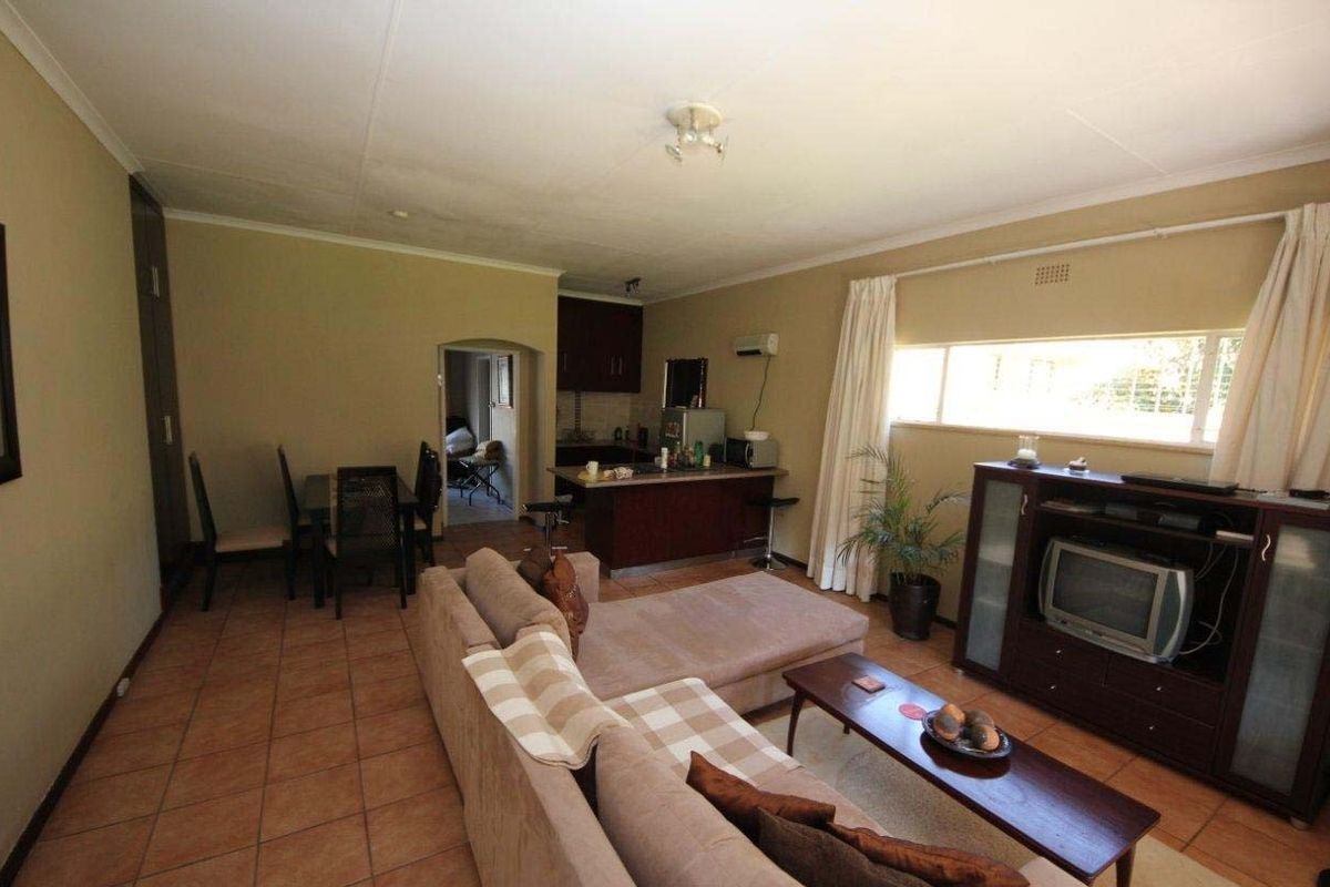 Open-plan living and dining area featuring tiled flooring, a functional kitchen with island, and an integrated air conditioning unit.