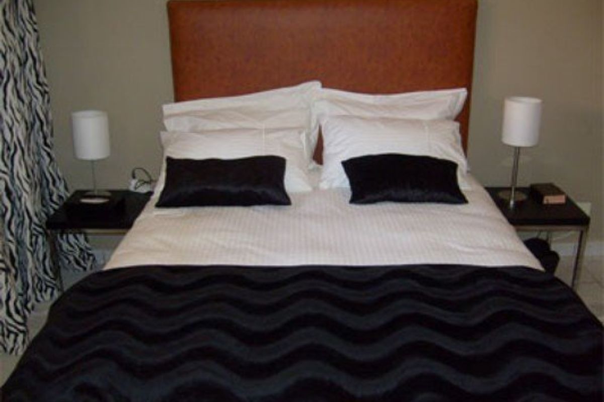 A bedroom featuring a central bed with a headboard, flanked by two side tables.