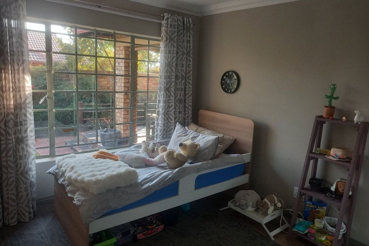 A bedroom featuring a large steel-framed window providing natural light and views of the garden area.