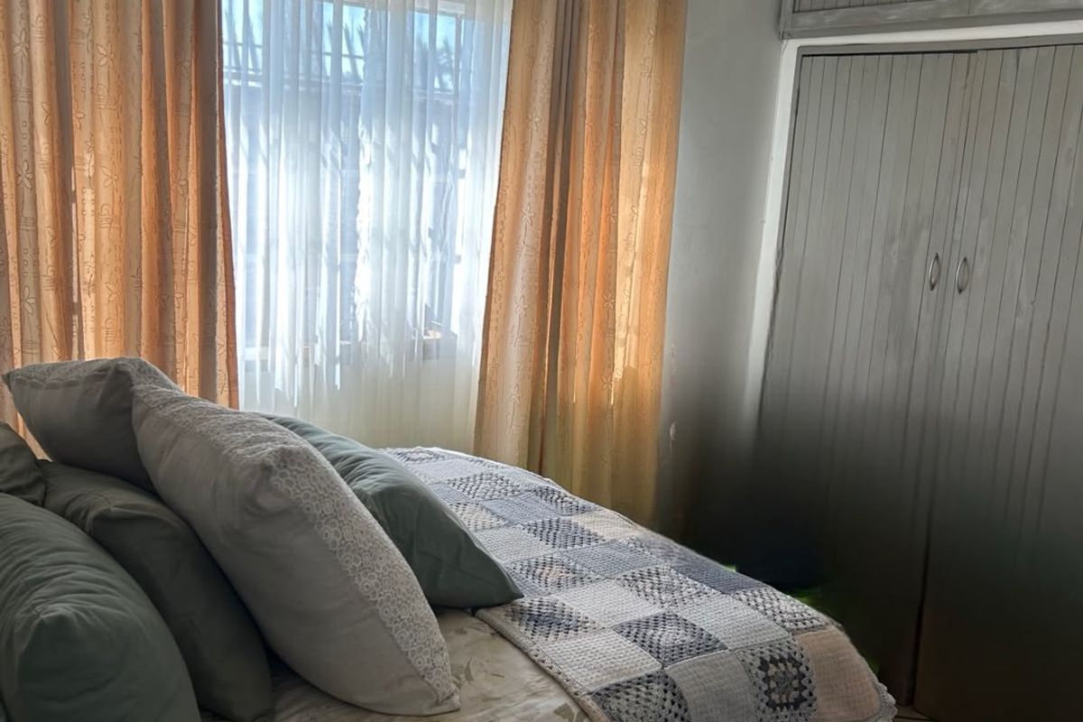 A bedroom featuring tiled flooring, a tongue and groove ceiling, and built-in wardrobe storage with overhead cupboards.
