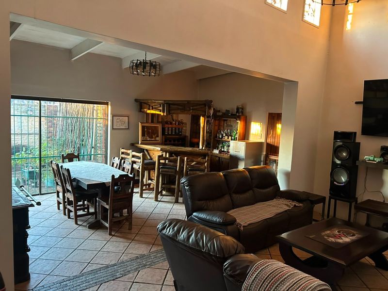 Spacious open-plan living and dining area featuring a built-in bar, tiled flooring, and large sliding doors leading to the outdoor space.