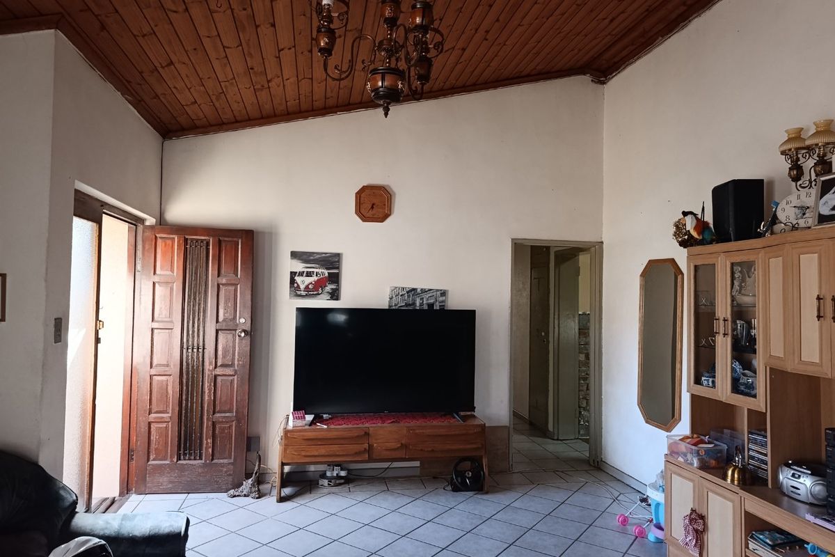 Living room featuring a raked timber-clad ceiling, ceramic tiled flooring, and a solid timber entrance door.