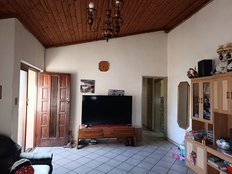 Living room featuring a raked timber-clad ceiling, ceramic tiled flooring, and a solid timber entrance door.