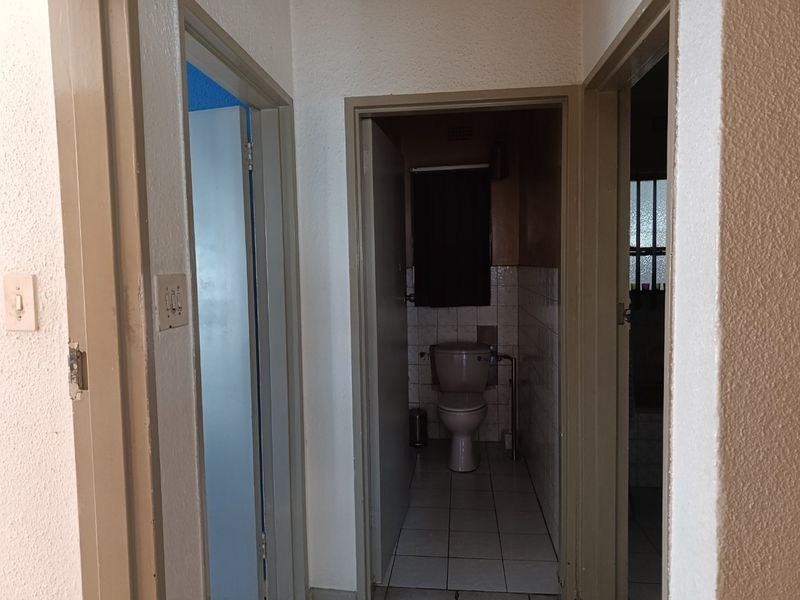 A view from a hallway looking into a small bathroom with tiled flooring and a standard toilet fixture.