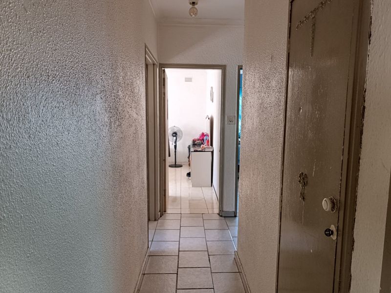 A functional hallway featuring tiled flooring and a built-in cupboard, providing access to adjacent rooms within the home.