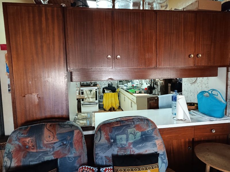 A dated kitchen featuring traditional wooden cabinetry, a laminate countertop, and a tiled splashback, offering potential for a modern renovation.