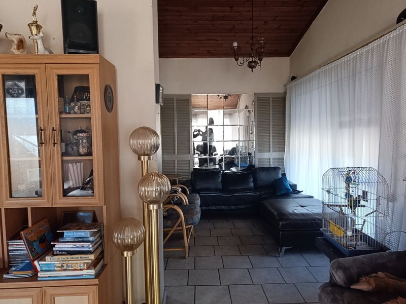 Living room featuring a vaulted timber-clad ceiling, tiled flooring, and a decorative mirrored wall panel, offering a traditional aesthetic with potential for modernization.