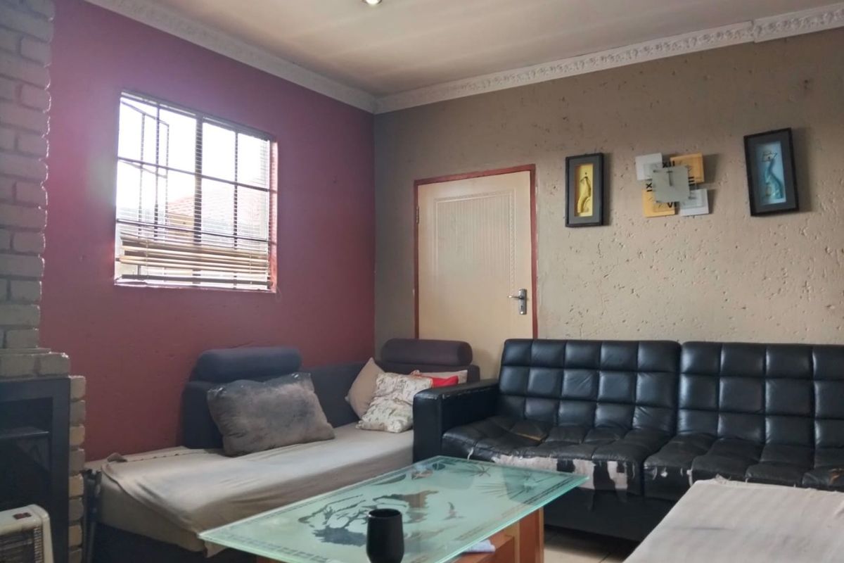 Living room featuring a brick fireplace, tiled flooring, and decorative ceiling cornicing, offering a functional space with potential for cosmetic updates.