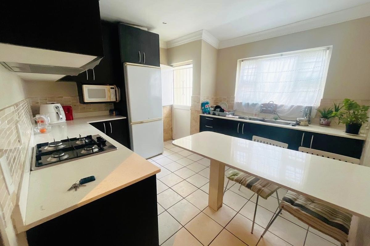 Functional kitchen featuring dark cabinetry, stone countertops, gas hob, extractor fan, and tiled flooring with direct access to the exterior.