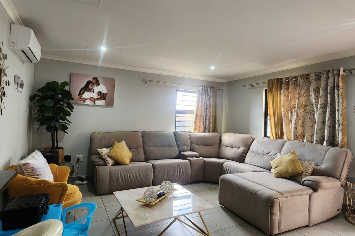 A well-maintained living room featuring tiled flooring, recessed downlighting, and a wall-mounted split-system air conditioning unit.