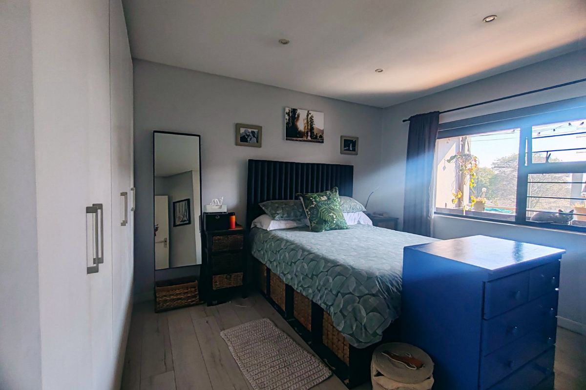 A well-lit bedroom featuring built-in cupboards, laminate flooring, and recessed downlights, offering a comfortable and functional living space.