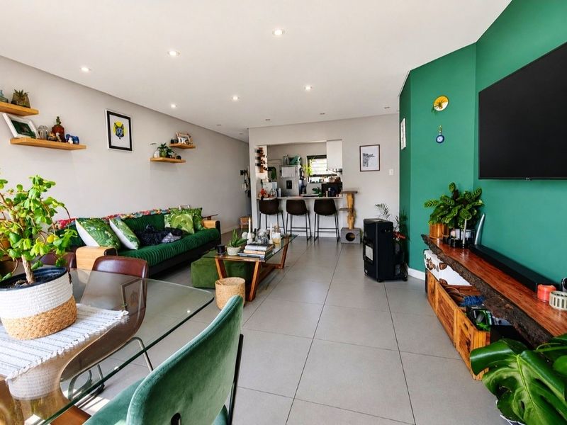 Spacious open-plan living and dining area featuring modern tiled flooring, recessed lighting, and a functional kitchen breakfast bar with a vibrant accent wall.