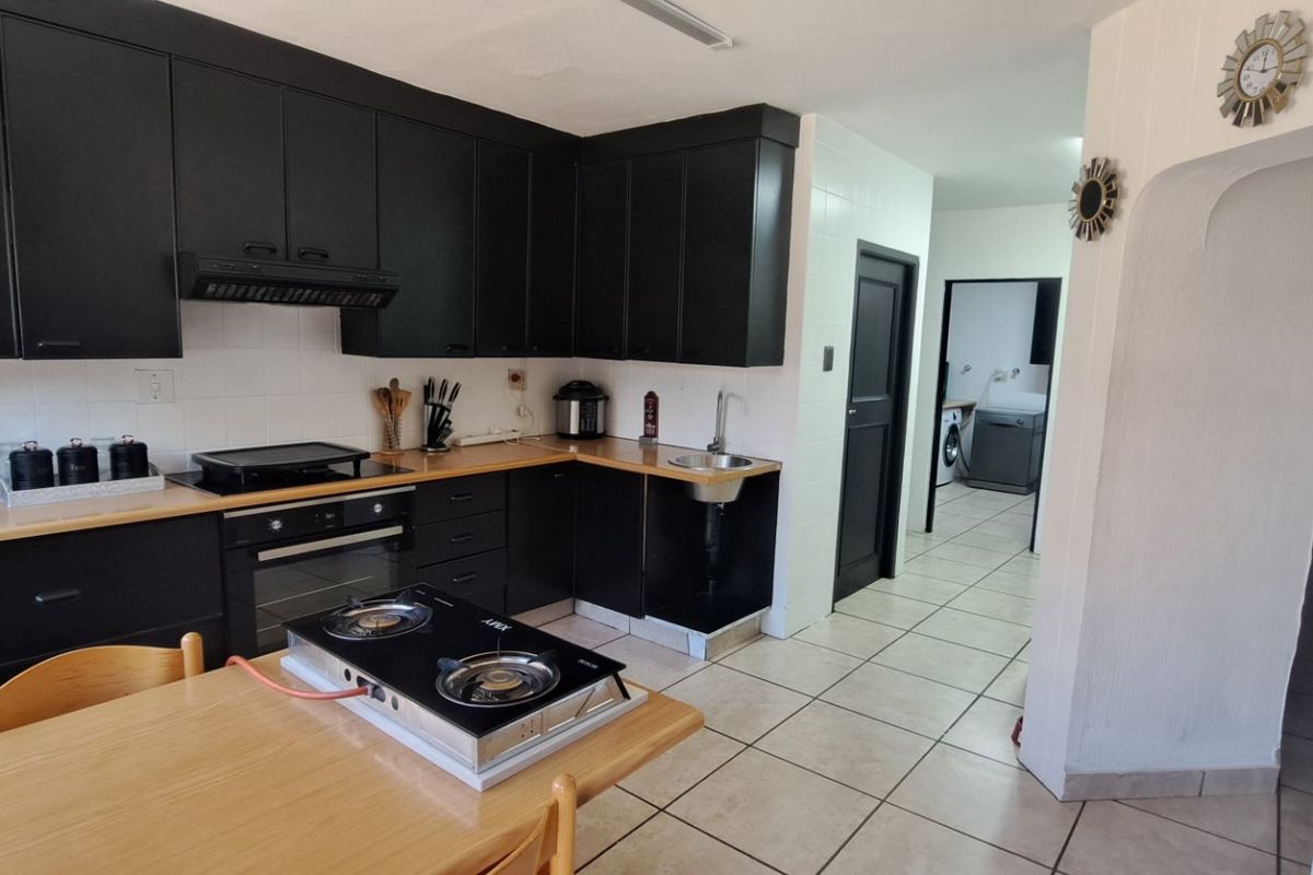 Kitchen featuring black cabinetry, tiled flooring, and a built-in oven, with an adjacent utility area visible through the doorway.