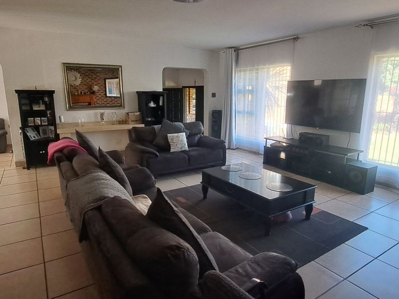 Spacious living room featuring ceramic floor tiles, large windows with security bars, and an open-plan layout leading to adjacent rooms.