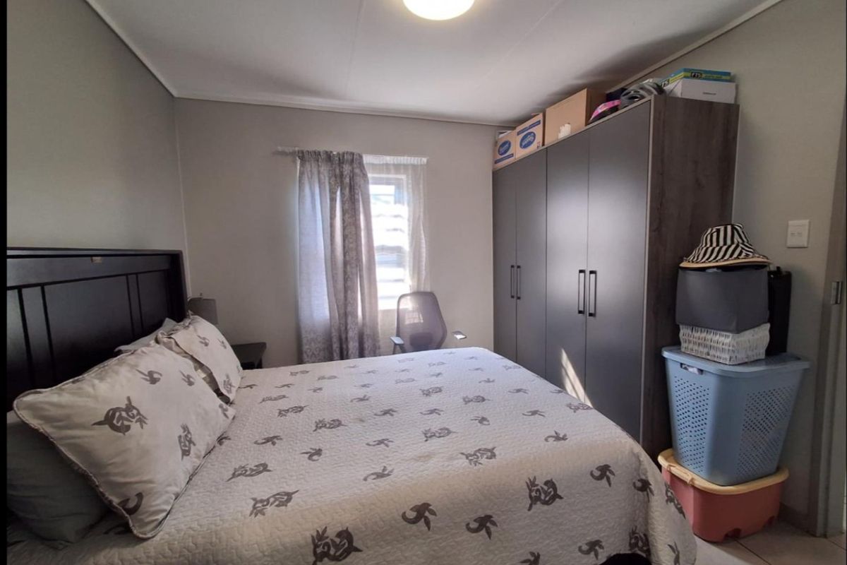 A functional bedroom featuring a built-in wardrobe and tiled flooring, providing a practical space with neutral wall finishes.