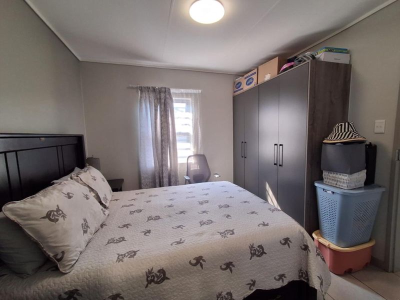 A functional bedroom featuring a built-in wardrobe and tiled flooring, providing a practical space with neutral wall finishes.