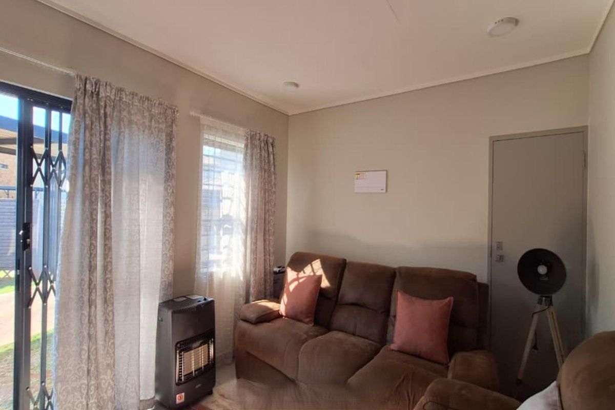 A living room featuring neutral walls, recessed lighting, and a sliding glass door with a security gate providing access to the outdoor area.