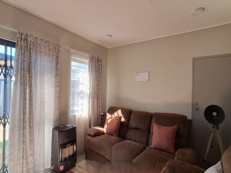 A living room featuring neutral walls, recessed lighting, and a sliding glass door with a security gate providing access to the outdoor area.