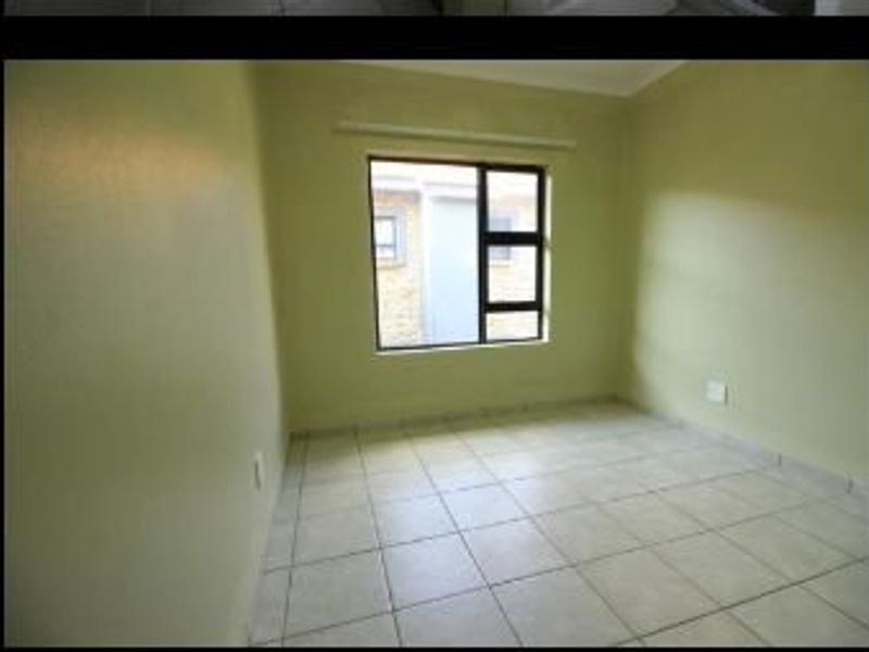An empty bedroom featuring tiled flooring and an aluminium window frame, providing a neutral canvas for potential interior design updates.