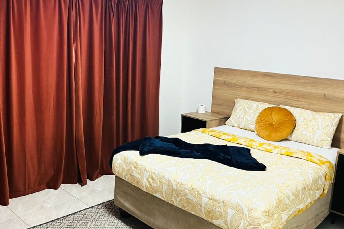 A well-maintained bedroom featuring neutral tiled flooring, a built-in wooden headboard, and floor-to-ceiling curtains.
