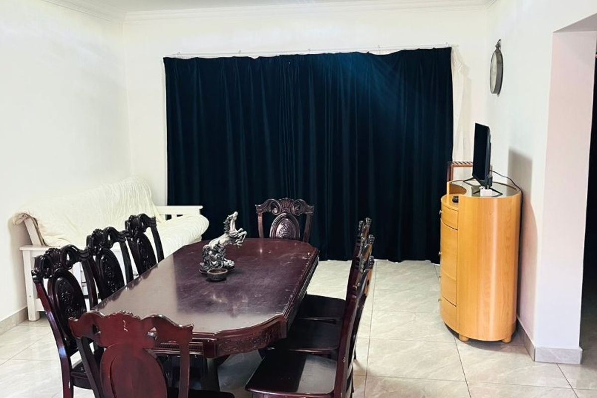 A dining room featuring neutral tiled flooring and classic ceiling cornicing, providing a functional space for family meals.
