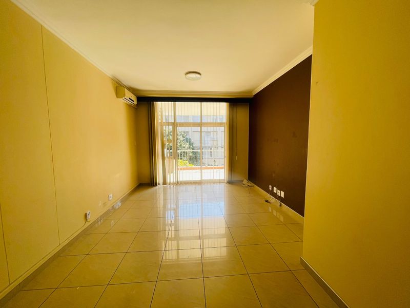 An empty living room featuring tiled flooring, a split-system air conditioner, and a large sliding glass door providing access to an outdoor area.