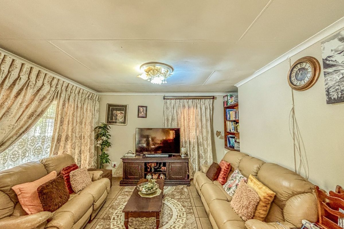 A comfortable living room featuring tiled flooring, built-in shelving, and decorative ceiling coving, providing a functional and traditional living space.