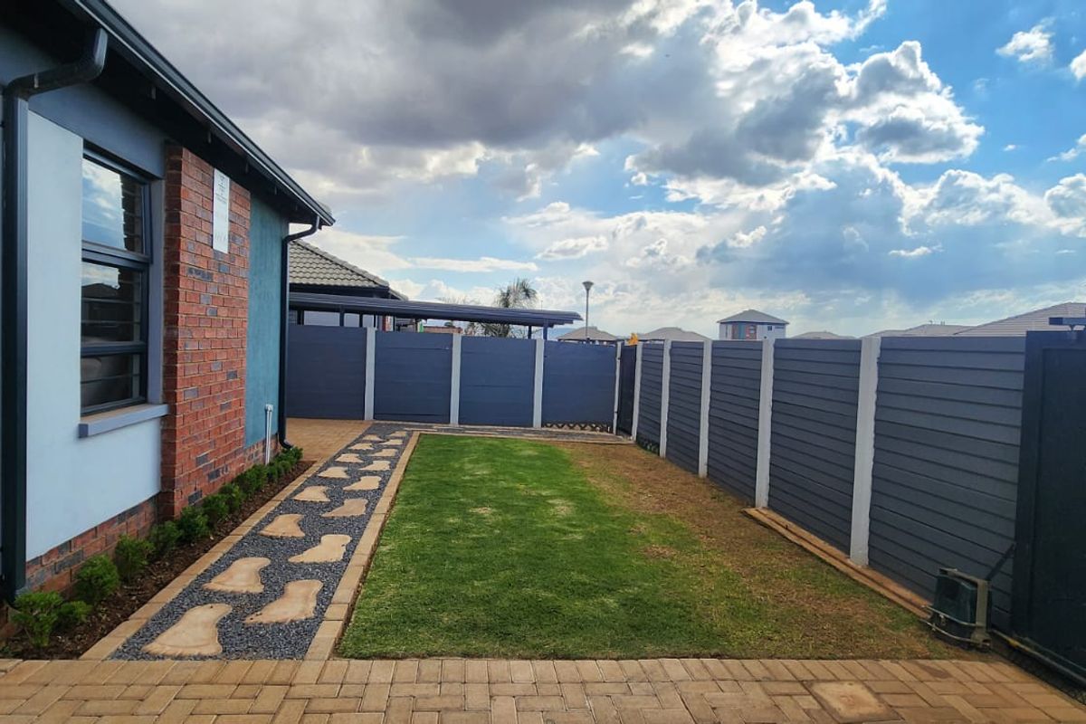 A well-maintained rear garden featuring a paved walkway, manicured lawn, and modern perimeter fencing, providing a clean and private outdoor space.