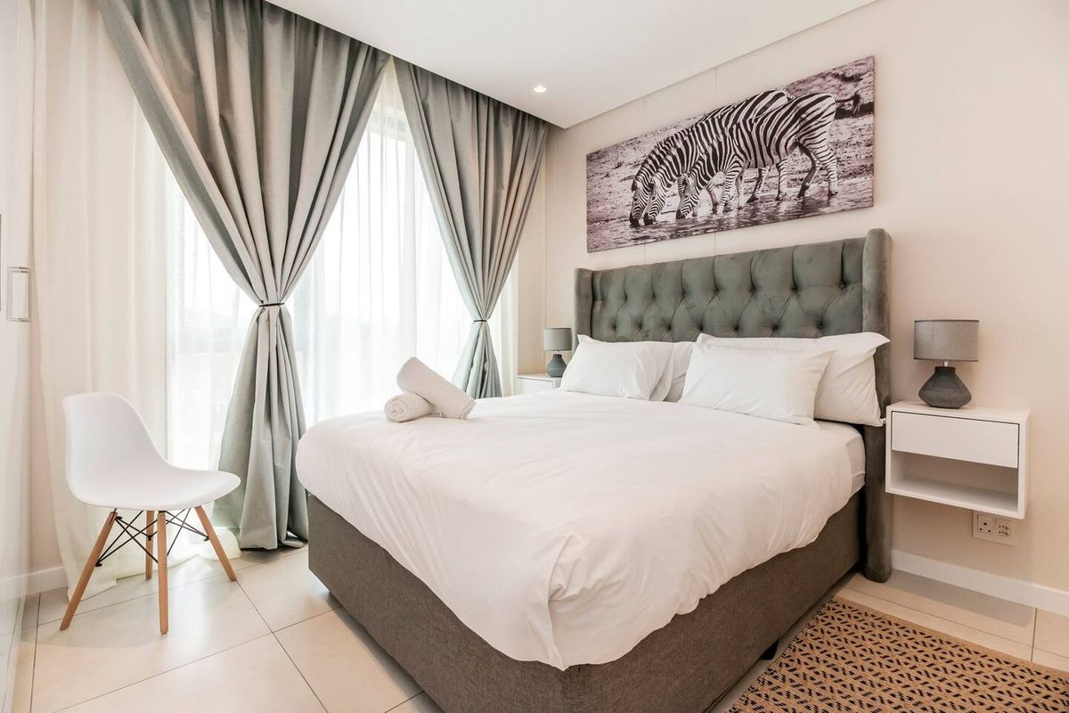 A well-maintained bedroom featuring tiled flooring, recessed lighting, and a large sliding glass door providing natural light.