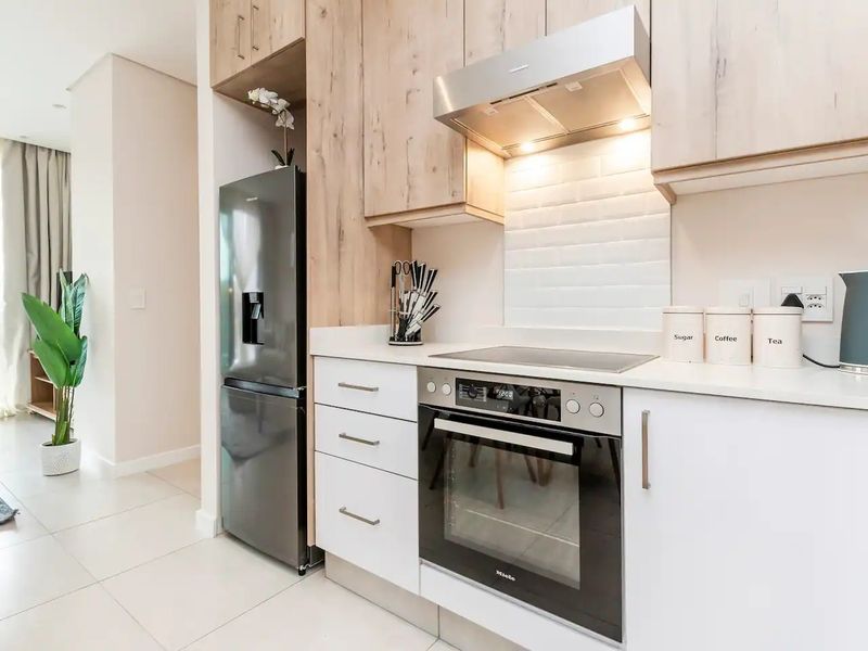 Modern kitchen featuring light wood and white cabinetry, stone countertops, subway tile backsplash, and high-quality built-in stainless steel appliances.