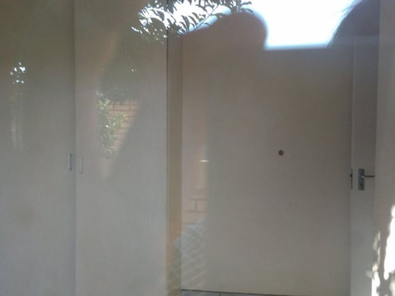 A bedroom interior featuring built-in cupboards with a glossy finish, captured with significant glare and reflection.