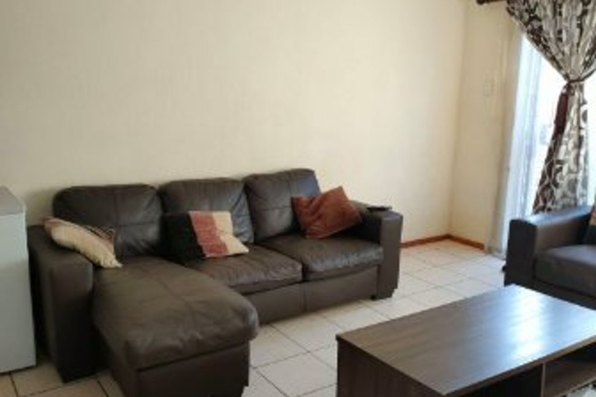 A living room featuring neutral tiled flooring and a sliding glass door providing access to the exterior.