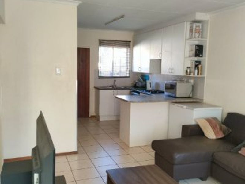 Open plan living area featuring a functional kitchen with built-in cabinetry and tiled flooring throughout the space.
