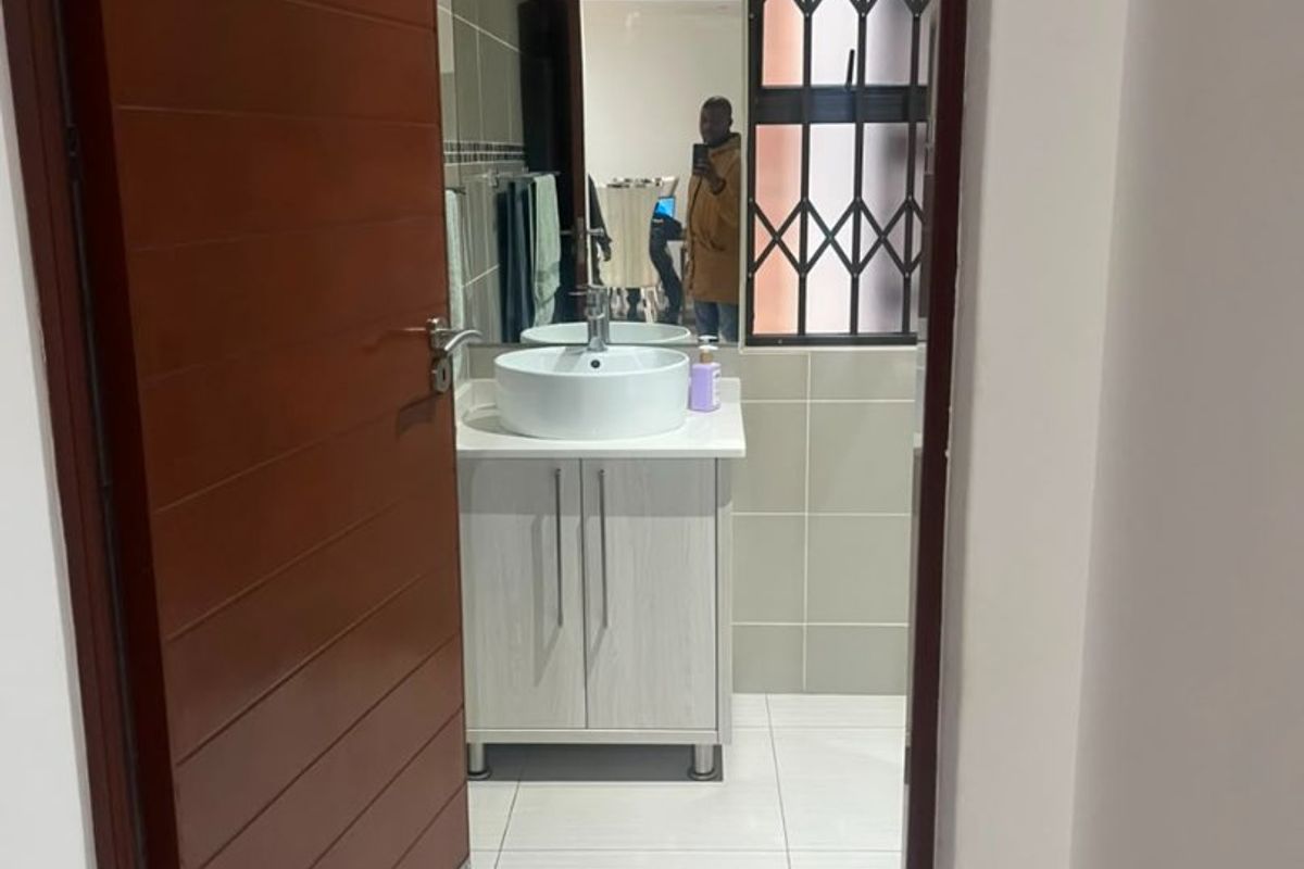A modern bathroom featuring a vessel sink, vanity cabinet, and neutral wall and floor tiling.