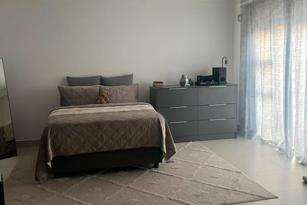 Spacious bedroom featuring neutral tiled flooring, recessed downlighting, and large sliding glass doors that provide ample natural light.