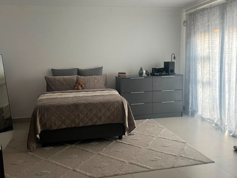 Spacious bedroom featuring neutral tiled flooring, recessed downlighting, and large sliding glass doors that provide ample natural light.