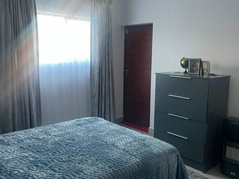 A well-maintained bedroom featuring recessed downlighting, decorative coving, and a solid timber door, offering a clean and functional living space.
