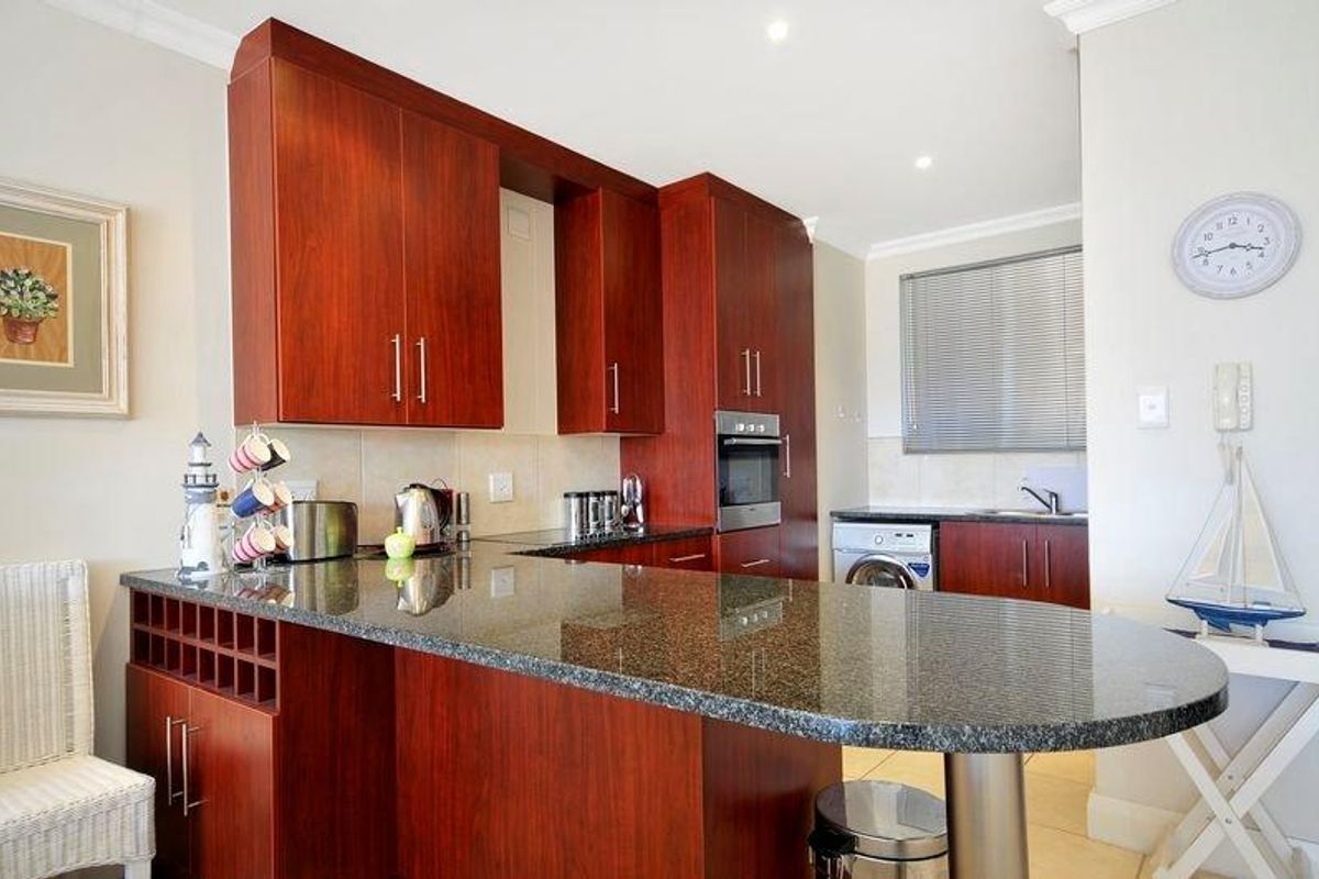 A functional kitchen featuring cherry wood cabinetry, granite countertops, a built-in oven, and an integrated laundry area with a washing machine.