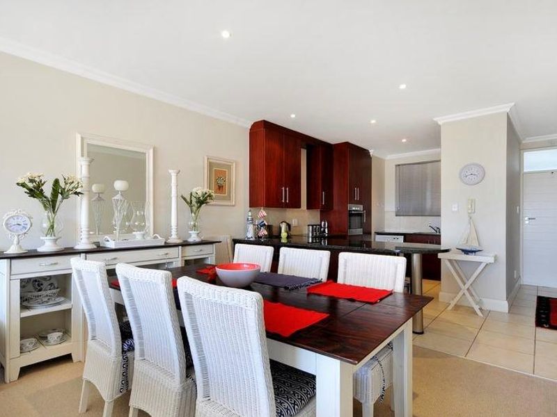Open-plan living and dining area featuring a modern kitchen with dark wood cabinetry, granite countertops, and integrated appliances, flowing into a bright dining space.