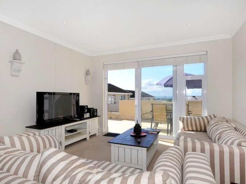 A bright and well-maintained living room featuring recessed lighting, neutral carpeting, and large sliding glass doors providing access to an outdoor balcony area.