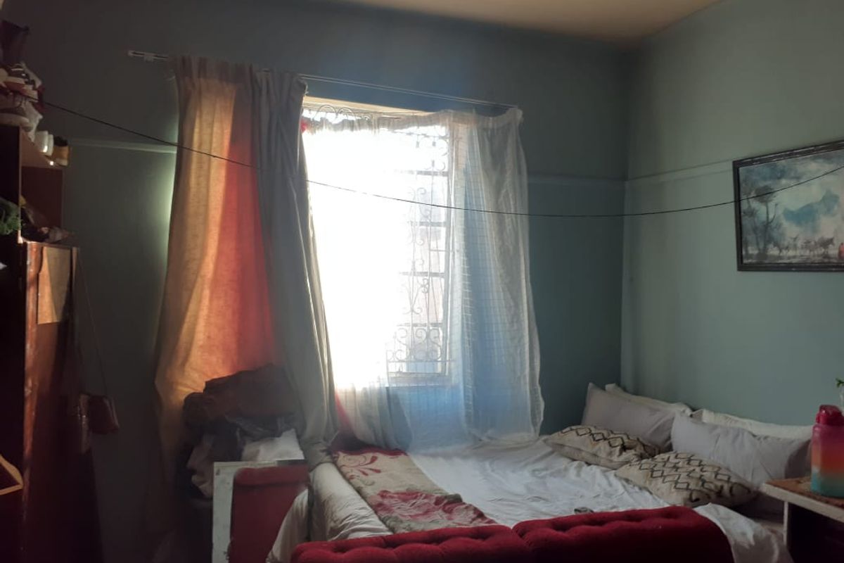 A bedroom featuring a window with security bars and a traditional picture rail, requiring cosmetic updates to improve the overall aesthetic.